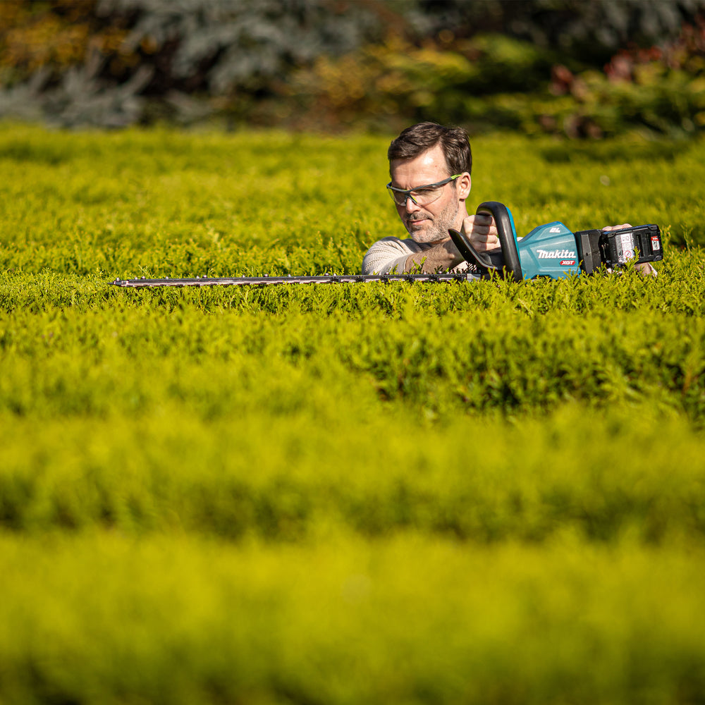 Makita - Makita UH007GZ XGT® 40Vmax BL Hedge Trimmer 40V Bare Unit - Man trimming hedge with Makita cordless hedge trimmer. - imagen 6