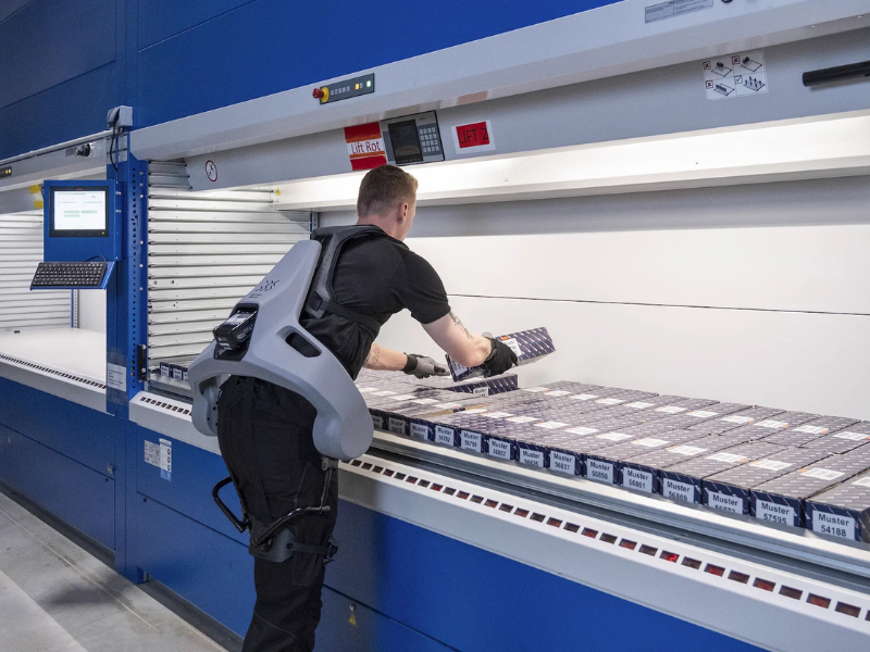 Person using a back exoskeleton to handle boxes in a warehouse setting