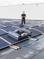 Person standing on a rooftop with solar panels and cleaning equipment. - imagen 14