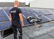 Person wearing a black 'omobil' shirt standing on a rooftop with solar panels and cleaning equipment. - imagen 15