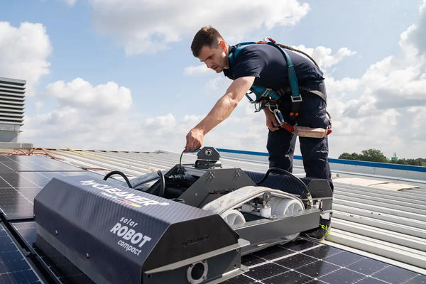 Person operating a solar panel installation robot on a rooftop