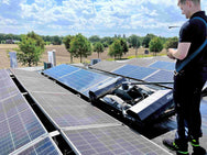 Person working on solar panels on a rooftop with a clear sky and trees in the background - imagen 3