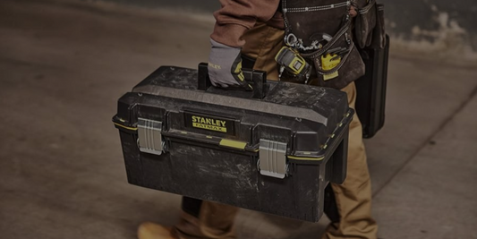 Person holding a Stanley toolbox with a blurred background
